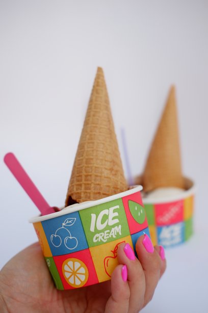 两份巧克力开心果冰淇淋，配有纸板碟中的威化杯和塑料勺，白色背景图片下载