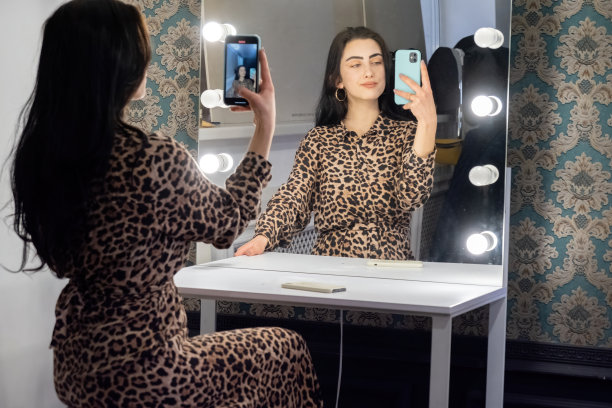 微笑的女子用手机对着镜子自拍图片下载