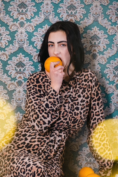 身穿豹纹长裙的年轻女子咬了一口橘子图片下载