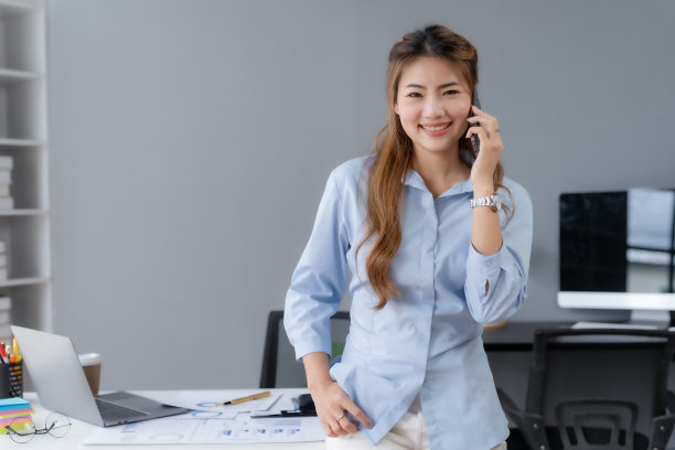 快乐美丽微笑的亚洲女商人在办公室工作时打电话。图片下载