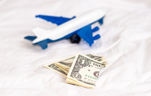 白色毯子上有飞机，美元和欧分硬币。旅游理念，旅游，与家人朋友一起旅游。预订机票。旅行社、广告横幅。节约钱,图片下载