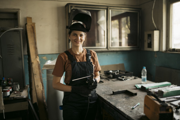 快乐的女工在车间用弧焊机工作图片下载