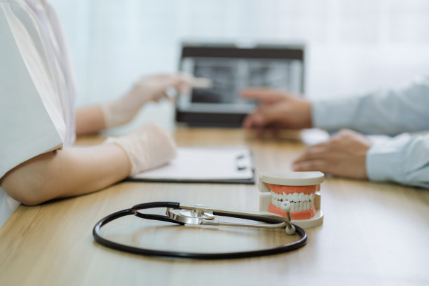 戴橡胶手套的女牙医在诊所用种植牙指导治疗，并通过片剂查看x线图像，口腔保健概念，选择性聚焦图片下载