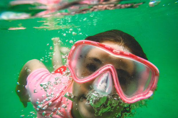 顽皮的游泳女孩戴着泳镜在水下游泳图片下载