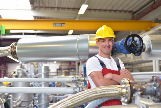 工业工厂现场成功的微笑工人/工程师肖像，戴着头盔图片下载