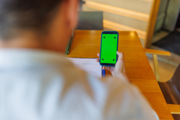 一位年轻的教师坐在餐厅里用手机进行数字银行业务图片下载