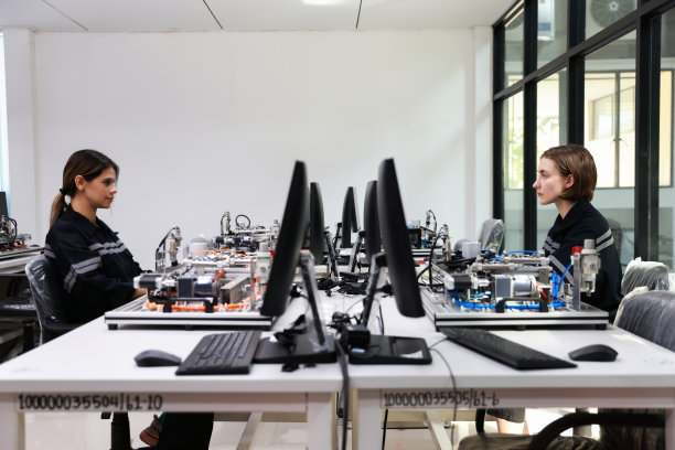 一对年轻的女电工工程师在一个培训课程上摆弄主板、电路板和使用桌面显示器图片下载