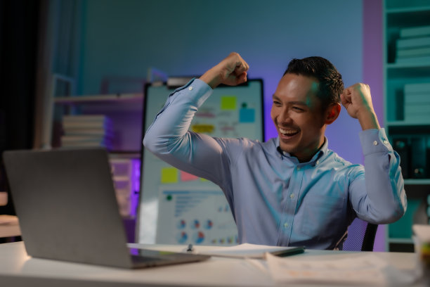 成就解锁。亚洲商人加班成功后高举双臂庆祝胜利。图片下载