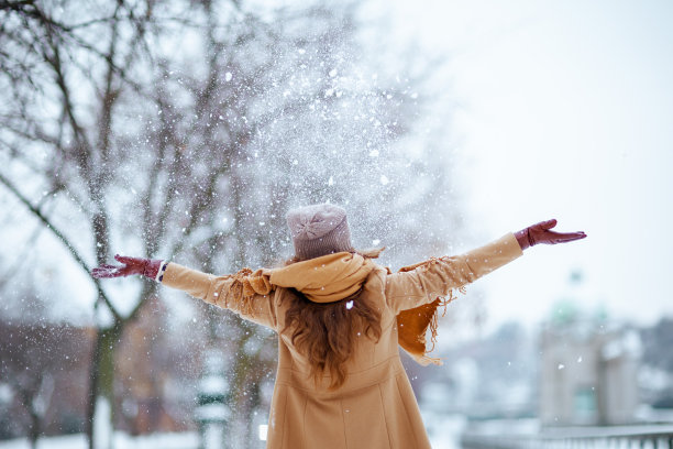 戴着棕色帽子和围巾的女人正在下雪图片下载
