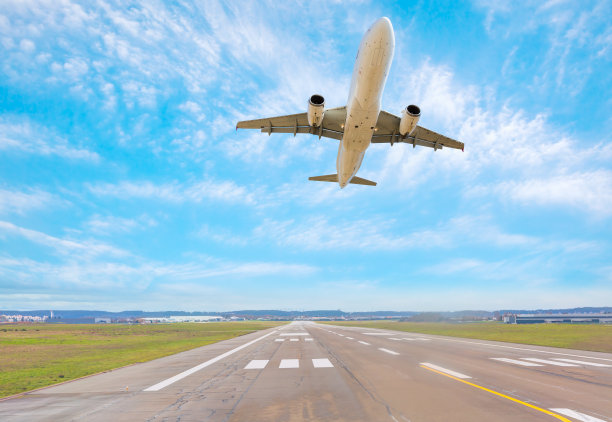 白色客机从机场起飞的跑道上飞过图片下载