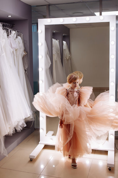 一个小女孩在精品店里对着镜子选衣服。图片下载