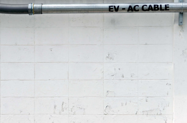 电缆电动汽车充电器的配线管安装在围栏水泥壁上图片下载