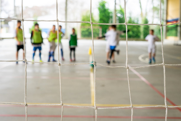 一群孩子练习五人制足球，把球踢进空球门。有选择性的重点图片下载