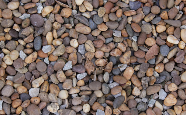 一堆岩石和砾石的照片，上面有一只小鸟，石墙上有很多不同颜色的岩石和砾石。图片下载