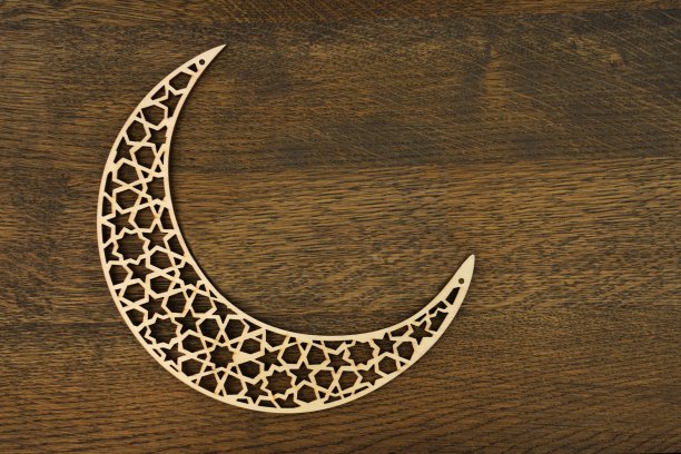 伊斯兰教的模式。新月与激光雕刻木材在棕色的木制背景。图片下载