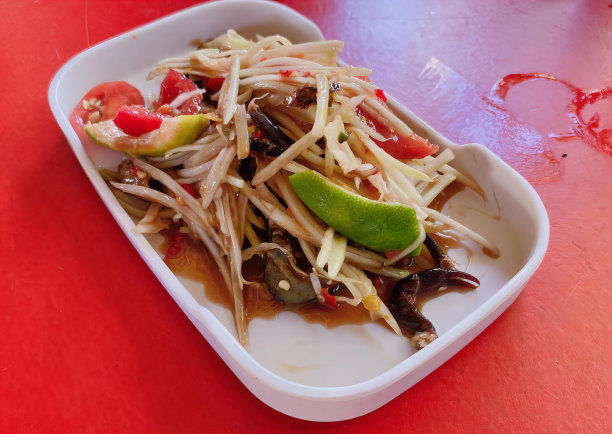 一盘食物的照片，有一个勺子和一个石灰，盘子里的食物放在一张红色的桌子上，上面铺着红色的桌布。图片下载