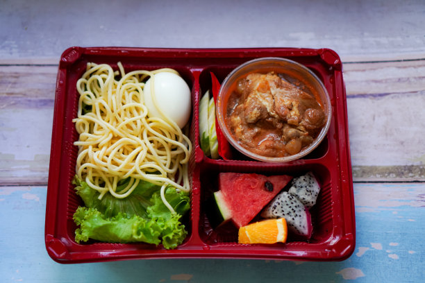 自制的盒式菜单上的意大利面酱烤鸡午餐在木制餐具的俯视图照片。图片下载