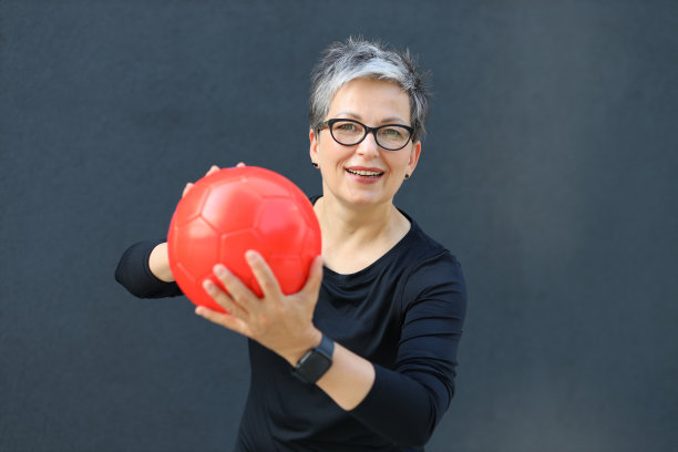 快乐运动的老年女士，自信的微笑。迷人的成熟女人，夏天快乐，站在墙边。永恒的美丽。图片下载