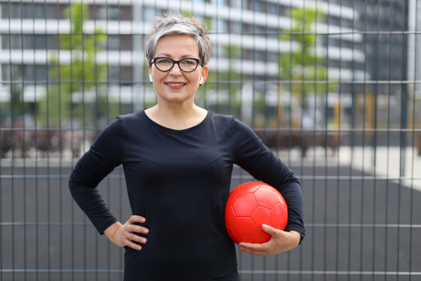 自信的资深女性在户外拿着球。拥抱运动而时尚的生活方式，散发优雅与幸福。图片下载