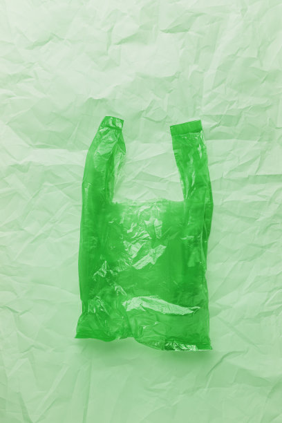 无塑料概念，俯视图皱巴巴的塑料袋皱巴巴的绿色皱纸背景，复制空间。一次性聚乙烯食品包装。生态趋势最小的风格照片，绿色单色图片下载