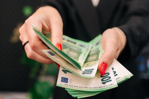 年轻女子商务女士，穿着别致的西装，穿着时尚，手里拿着一大笔欧元。业务和收入概念图片下载