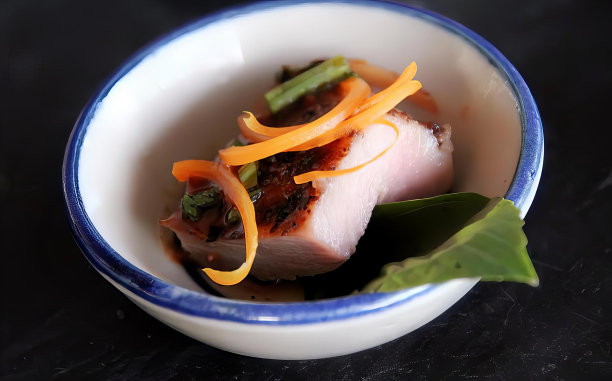 一张照片上的碗里有一片叶子和一块肉，汤碗里有肉和蔬菜放在黑色的桌子上。图片下载