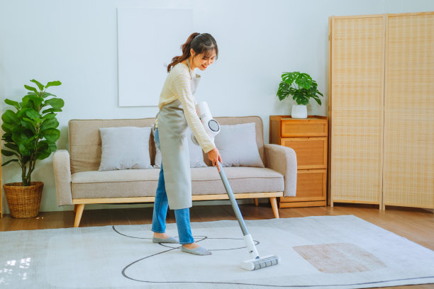 亚洲妇女使用真空吸尘器清洁地板。管理的概念图片下载