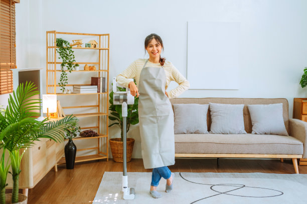 亚洲妇女使用真空吸尘器清洁地板。管理的概念图片下载