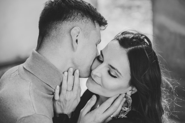 情侣接吻特写。男人自然地亲吻女人。新婚夫妇在教堂附近散步。日落时分，新娘和新郎在古庙的大石柱旁亲吻。黑白照片。俯视图图片下载