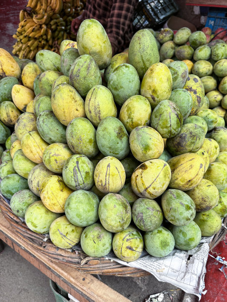 新鲜农产品市场展示的特写图像，大舍里芒果堆放在柳条筐里，香蕉束成堆，摊贩在背景中，焦点在前景图片下载