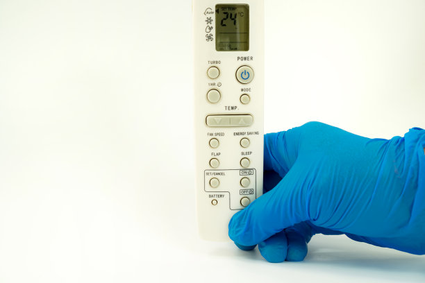 图片显示手拿着空调遥控器，温度调节在白色背景上图片下载