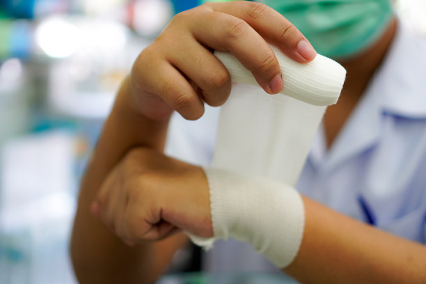 图片显示演示使用白色弹性网纱布绷带包裹受伤的手腕，步骤3。图片下载