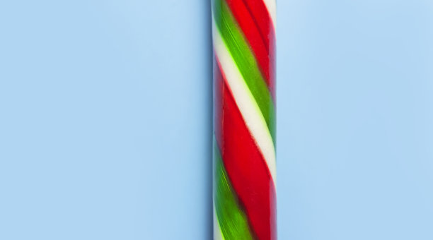 传统的圣诞棒棒糖，棒棒糖在蓝色背景上平铺俯视图微距照片。新年食品概念。节日装饰，甜味，焦糖。圣诞节日的象征、装饰图片下载