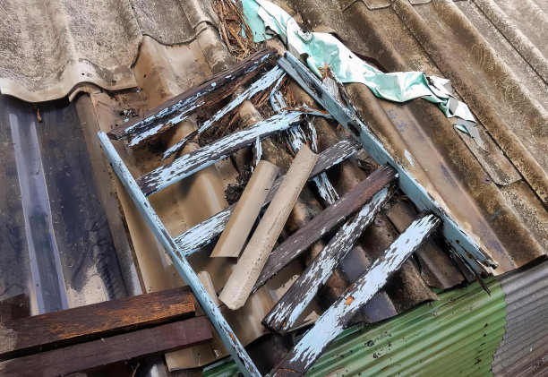 屋顶上一堆旧木头和金属的照片，屋顶上有锤子和金属片。图片下载