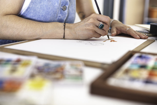 选择性地集中在一个插画家的手画她的作品在不同的水彩材料。图片下载