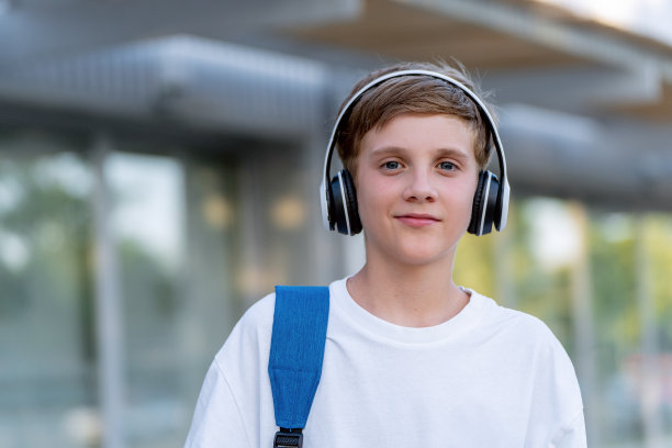 小男孩戴着耳机听音乐，看着相机的照片。图片下载