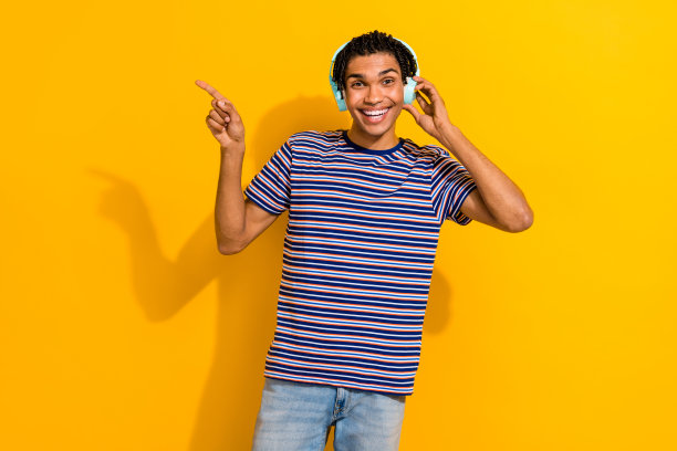 照片英俊时髦的男人与脏辫触摸耳机指导促销空白空间孤立的黄色背景图片下载