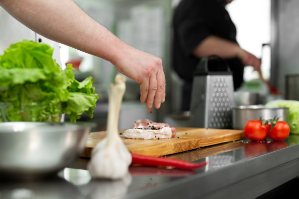 厨师在生牛排上撒胡椒。专业厨师用胡椒调味多汁的肉。图片下载