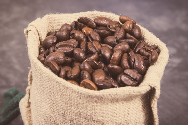 一堆深烘咖啡粒在黄麻袋。的照片图片下载