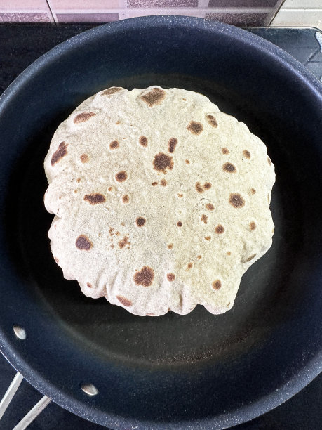特写图片，不粘锅里有膨胀的烤肉，用全麦面粉做成的薄饼，在厨房的炉子上烹饪，高架视图图片下载