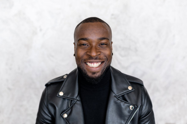 穿着时髦皮夹克的非裔美国男人看着镜头，开心地笑着图片下载