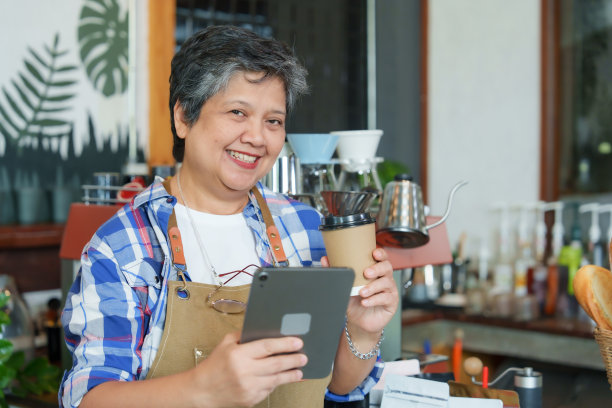 年迈的单身母亲抱着双臂站在美丽的女儿身边，眼中充满了幸福。每天早上准备开咖啡店，小的家庭生意。一个女人开了一家咖啡馆。图片下载