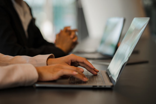 侧视图，女商人的手使用笔记本电脑休息，年轻女子在空白笔记本上写字，放在办公桌上与笔记本电脑键盘近距离的照片图片下载