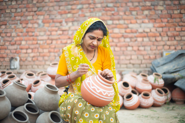 传统的印度妇女制陶艺术家在陶罐上绘画和装饰设计出售，手工艺，技能印度。图片下载