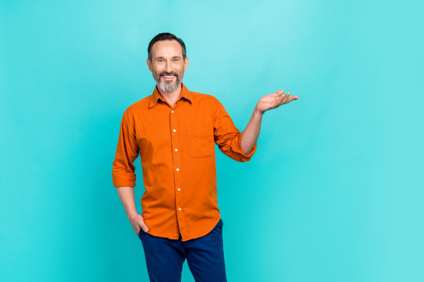 照片上的商人上了年纪，穿着橙色时髦的衬衫，手拿牌子，在海蓝宝石的背景上进行宣传图片下载
