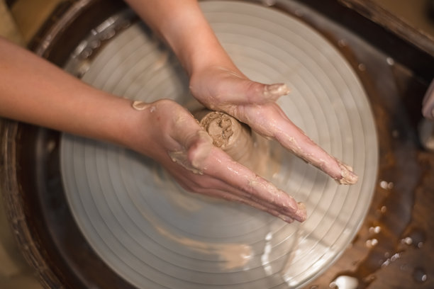 陶艺女工在陶艺作坊里用陶土制作陶罐图片下载
