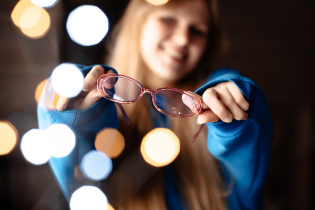 一个戴粉红色眼镜的女孩。一个穿蓝色连帽衫的女人。有灯光效果的照片图片下载