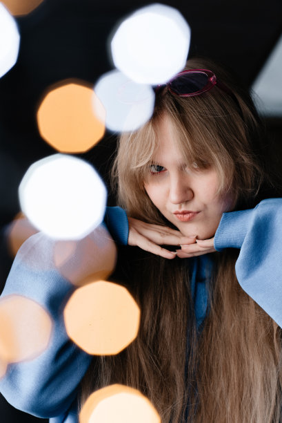 一个戴粉红色眼镜的女孩。一个穿蓝色连帽衫的女人。有灯光效果的照片图片下载