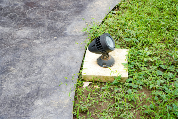 沿着房子外面走廊的草坪上安装的一个小LED聚光灯的图片。图片下载