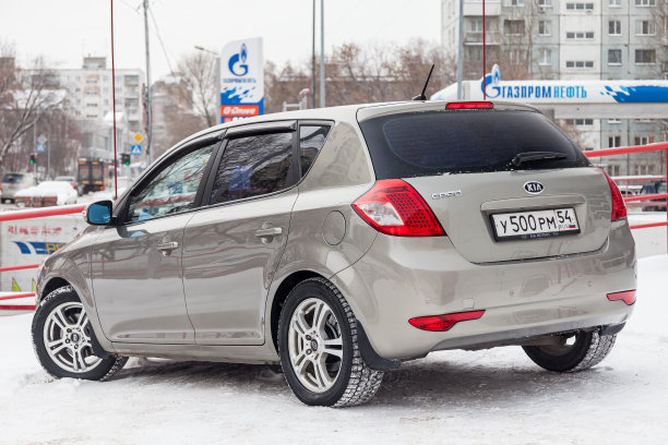 米色起亚Ceed前视图的汽车停车场与雪的背景在街道上。图片下载